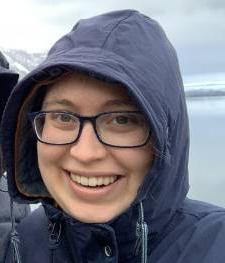 Smiling Emily Grantz outside in the rain with her hood on. 